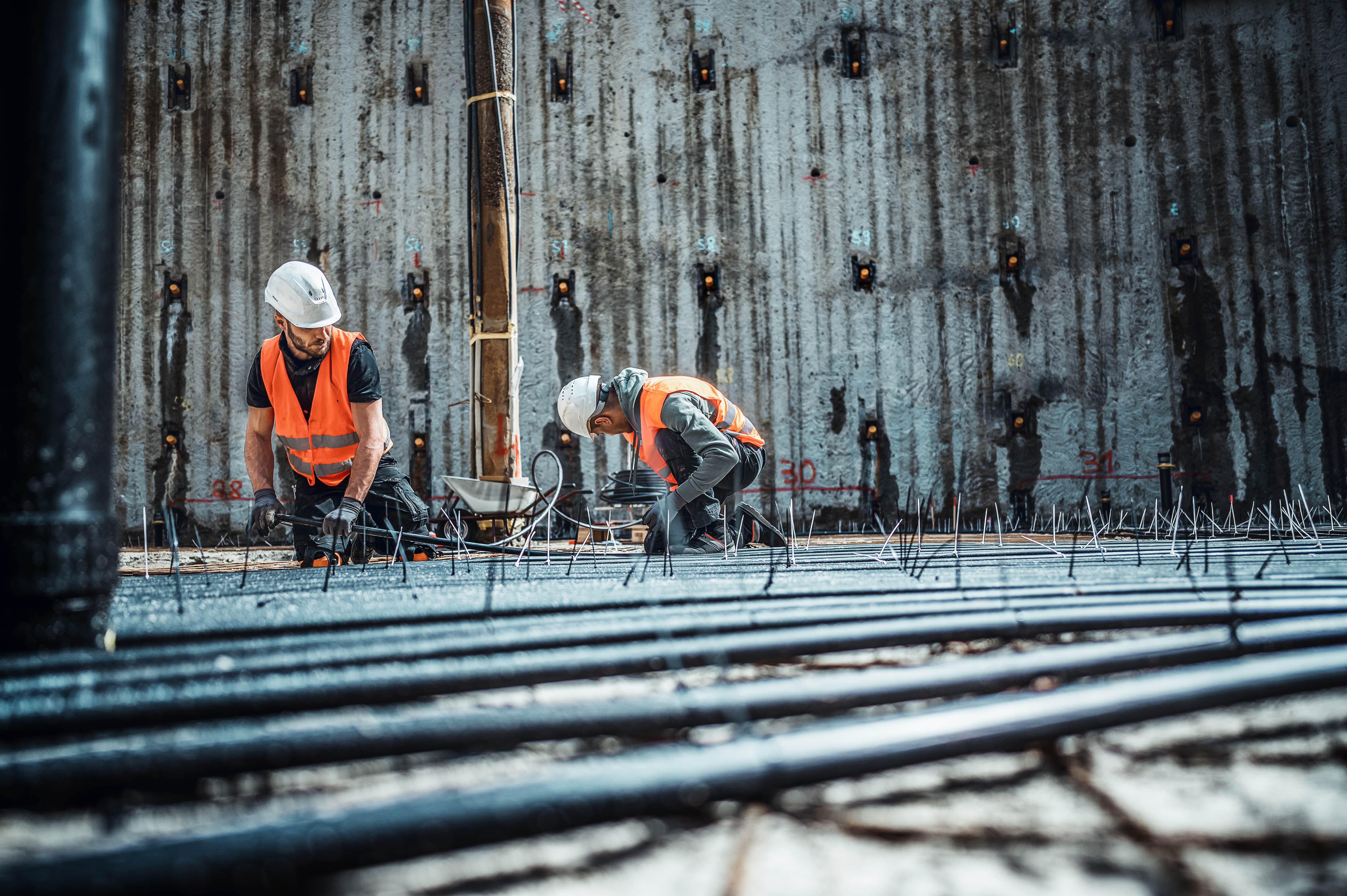 Bauer Resources Mitarbeiter bei der Rohrleitungsinstallation für Geothermie in einer Baugrube