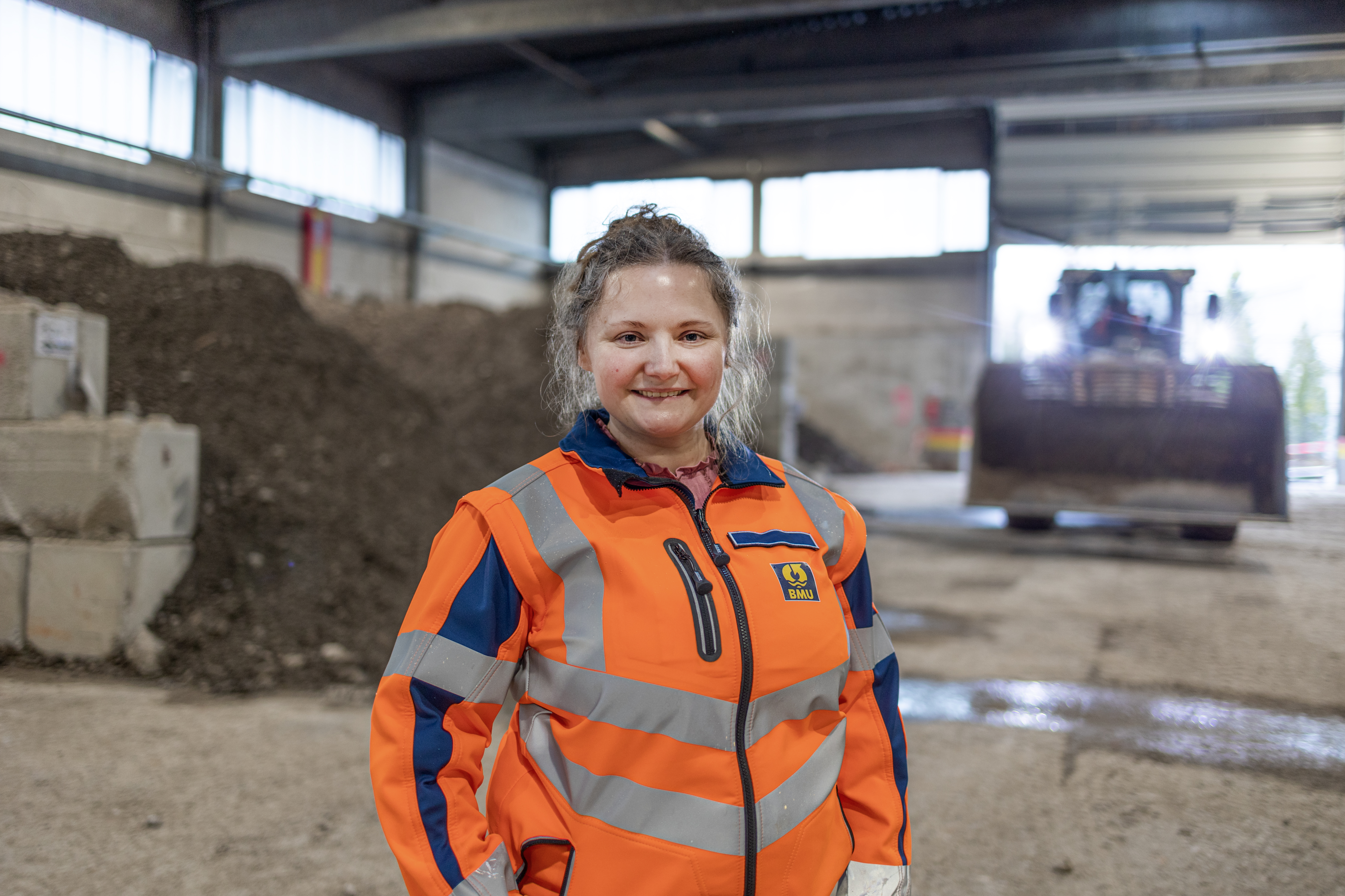 Hedwig Arbinger, Leiterin Bodenreinigungszentrum Weilheim, seitlich stehend vor Haufwerk in der Halle