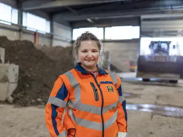 Hedwig Arbinger, Leiterin Bodenreinigungszentrum Weilheim, seitlich stehend vor Haufwerk in der Halle