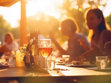 Personen an einem Tisch mit Snacks und Getränken in der Abendsonne 